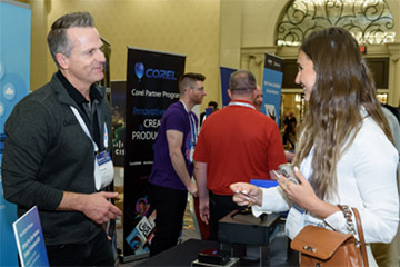 Exhibitor having a conversation with attendee holding their business card. 
